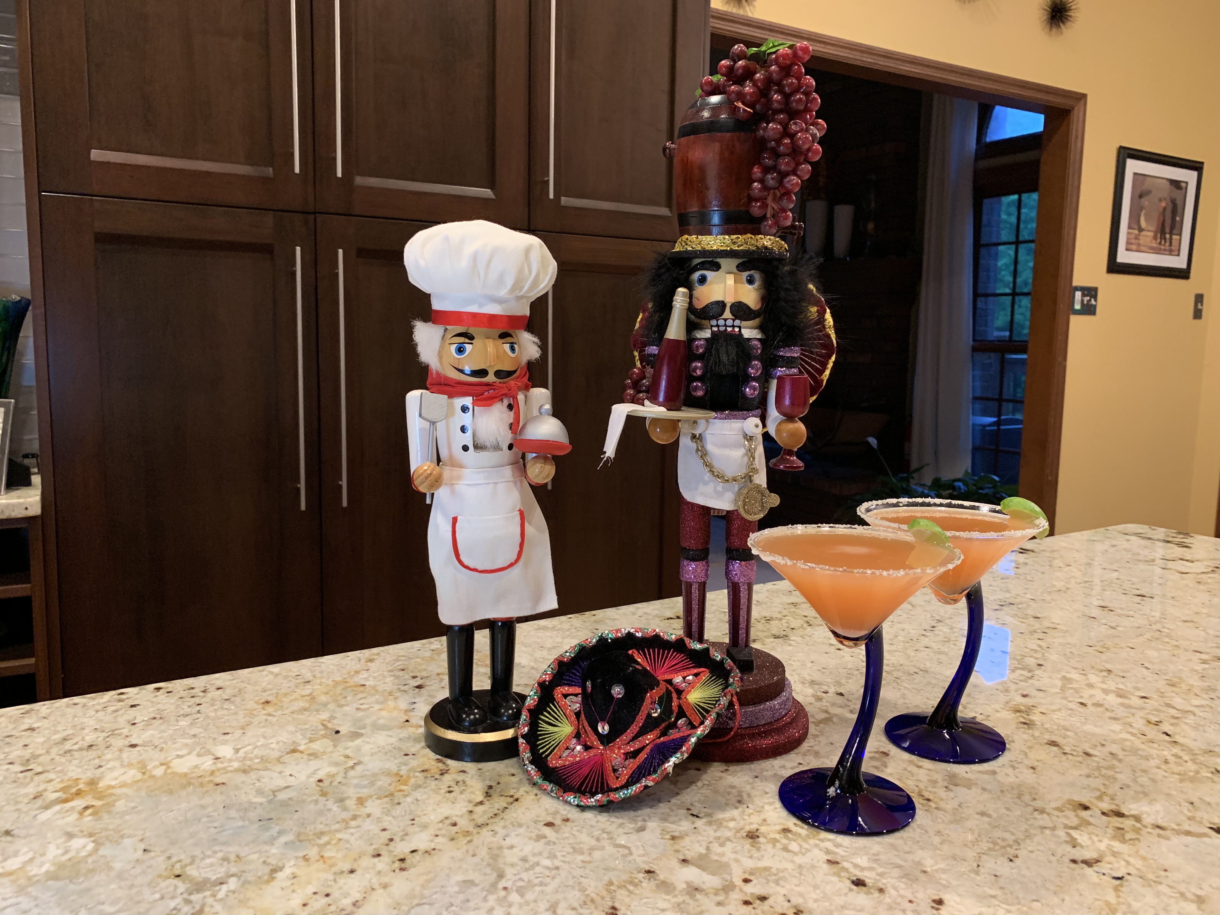 Two nutcrackers, a tiny sombrero and two orange colored cocktails in martini glasses.