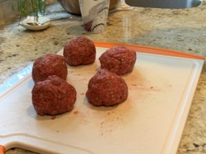 rolling meat into balls to form patties
