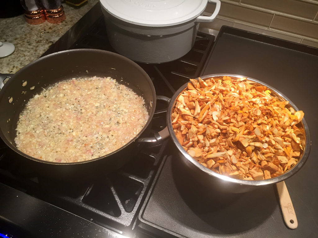skillet with sautéed shallots, bowl with chopped chanterelles on a stove top.