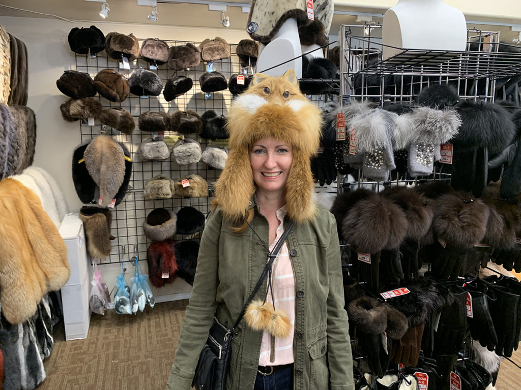 woman in fur store wearing a fox fur hat