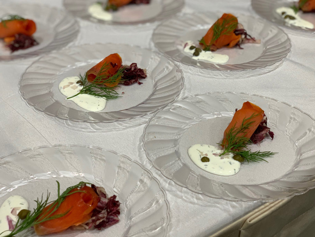 GravLox on clear plate on white table with sprig of dill and white sauce