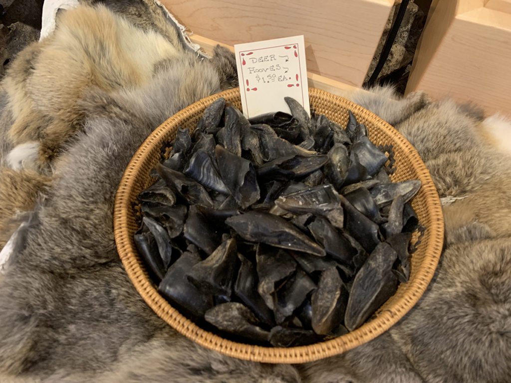 wooden bowl filled with deer hooves sitting on top of a animal fur skin