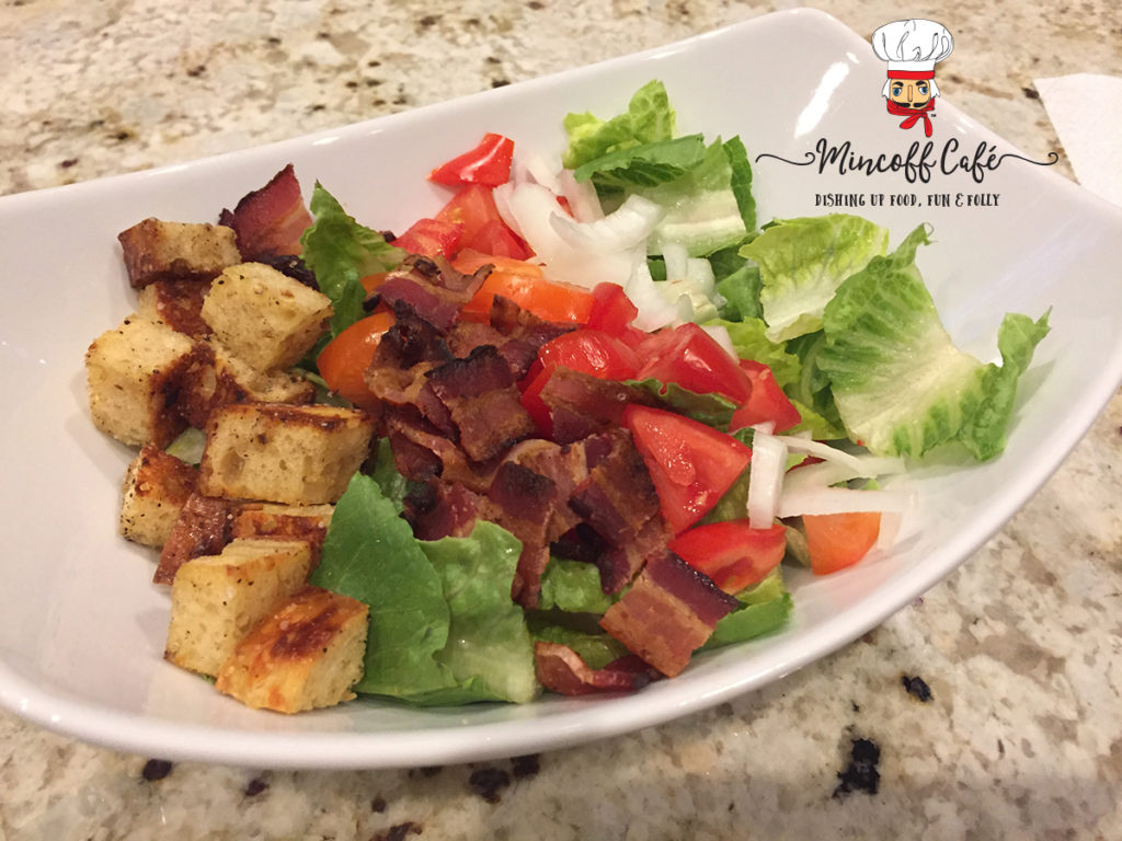 Bacon, lettuce, tomato, onions and croutons in a white bowl