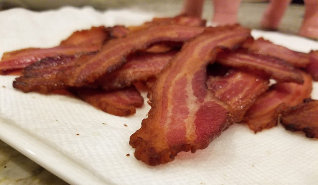 Close up image of pile of bacon on a white plate