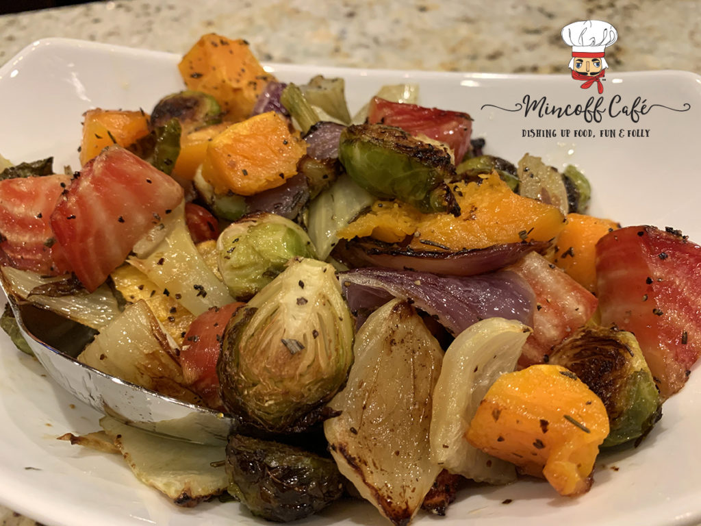 Colorful roasted vegetables ((butternut squash, red onions, brussles sprouts, fennel bulb and candy cane beet root) in a white bowl.