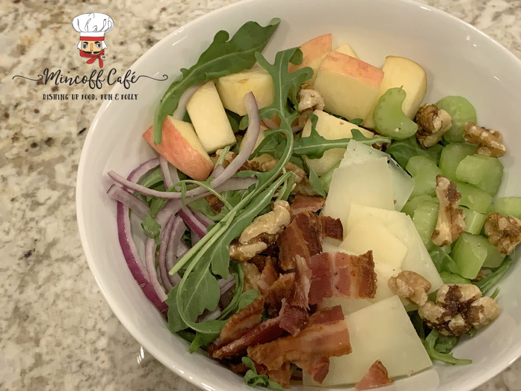 Bacon, Apple, celery, red onions, walnuts, manchego cheese and arugala salad in a while bowl