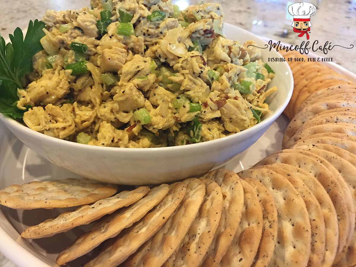 Beautiful Curry Chicken Salad in a white bowl, which inside another white dish that has round crackers circling the salad.
