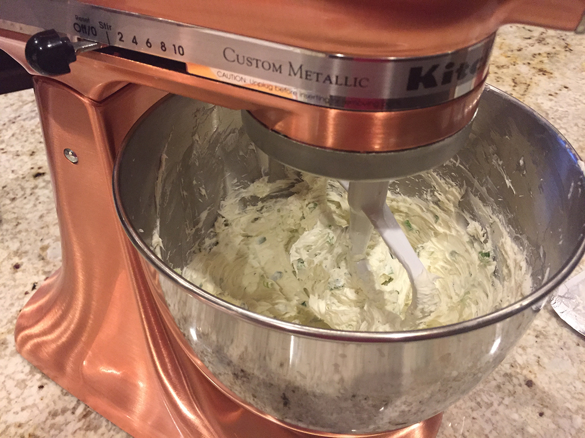 Cream cheese, green onions being mixed in a copper stand mixer.
