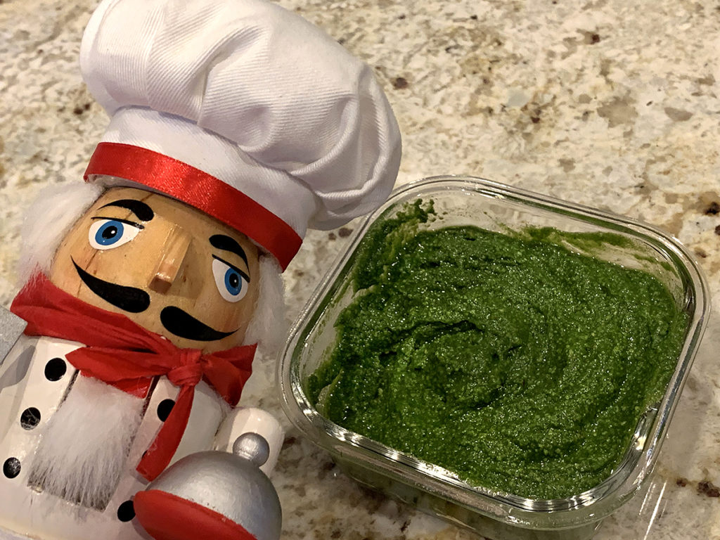 Stinging nettle pesto in a square glass dish. And a nutcracker who looks like a chef in the foreground.