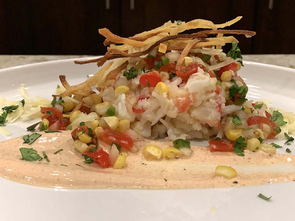 king crab, pico de gallo and chipotle cream sauce on a round white plate.