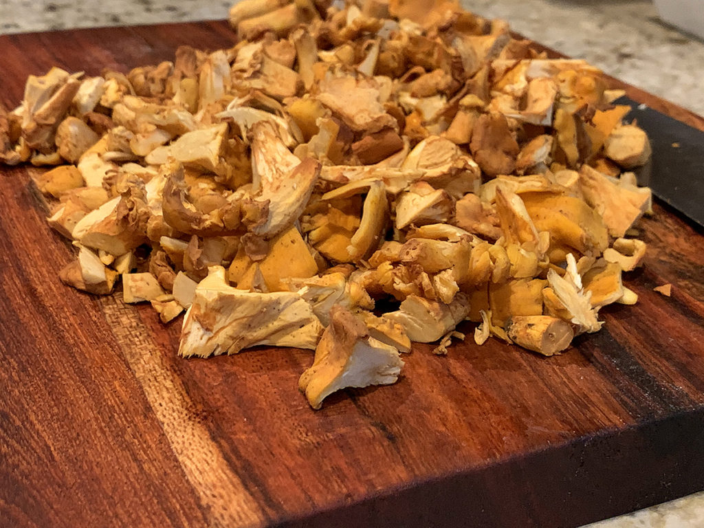 Rough chopped chanterelles on a wood board.