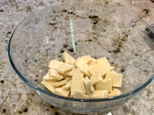 Chunks of white chocolate in a clear glass bowl.