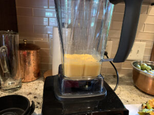 Pale yellow orange pawpaw fruit being pureed in a blender.