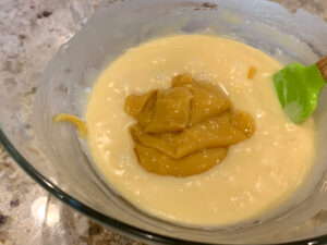 A dollop of orange pawpaw butter on top of white chocolate ganache in a clear bowl.