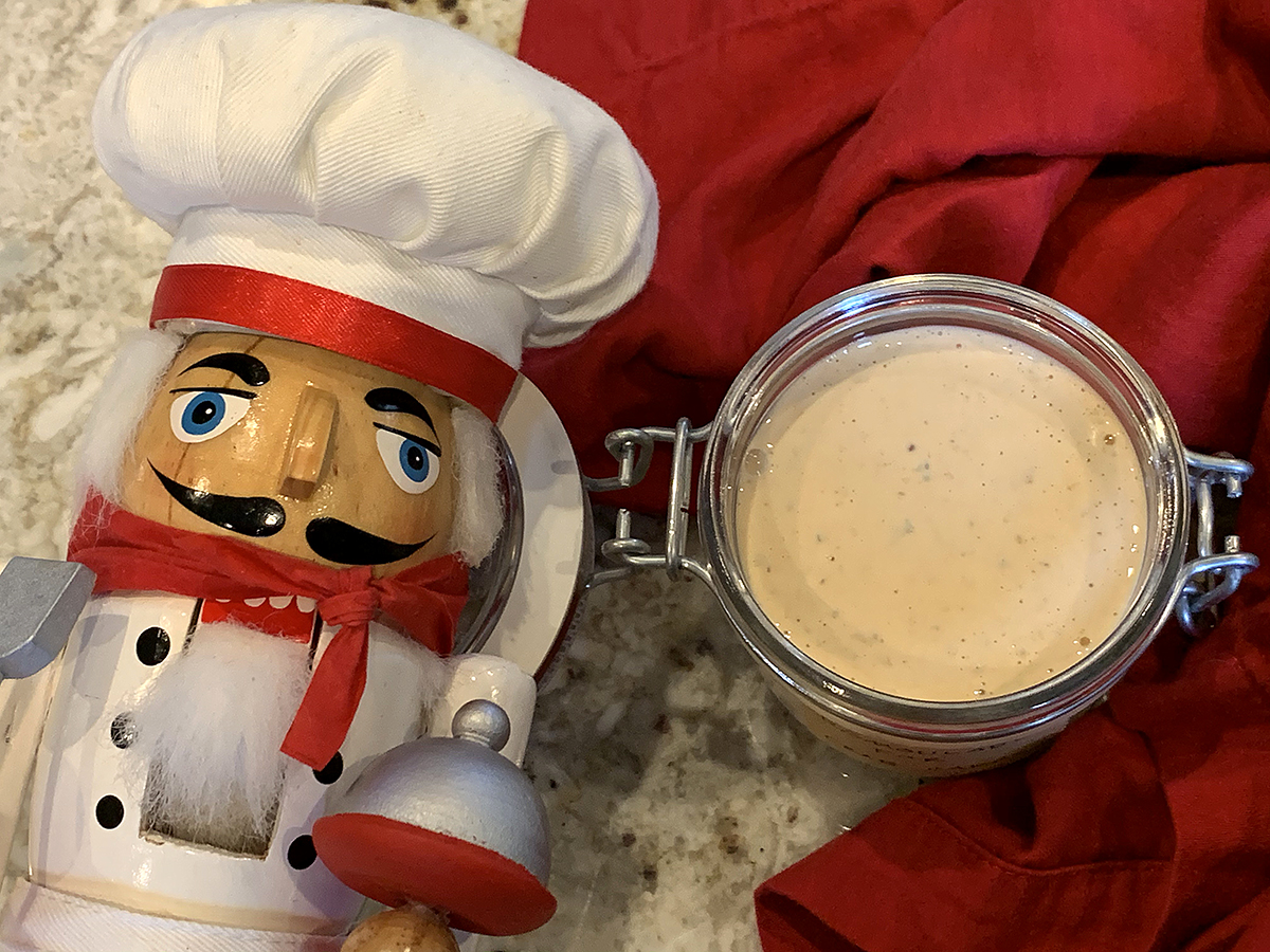 Pale orange sauce in a glass jar with a hinged lid. There also a nutcracker who looks like a chef in the foreground.