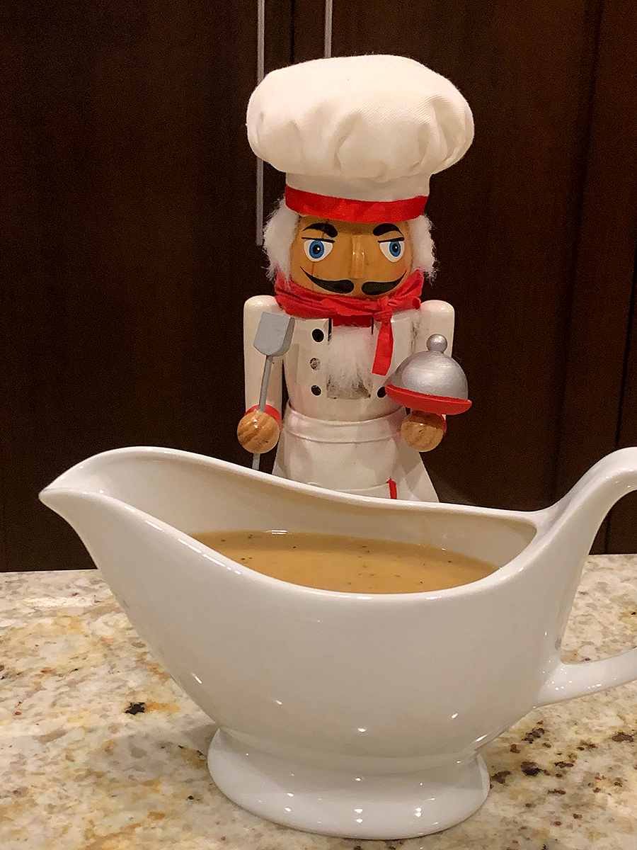 Tan gravy in a white gravy boat. There's a nutcracker who looks like a chef in the background.