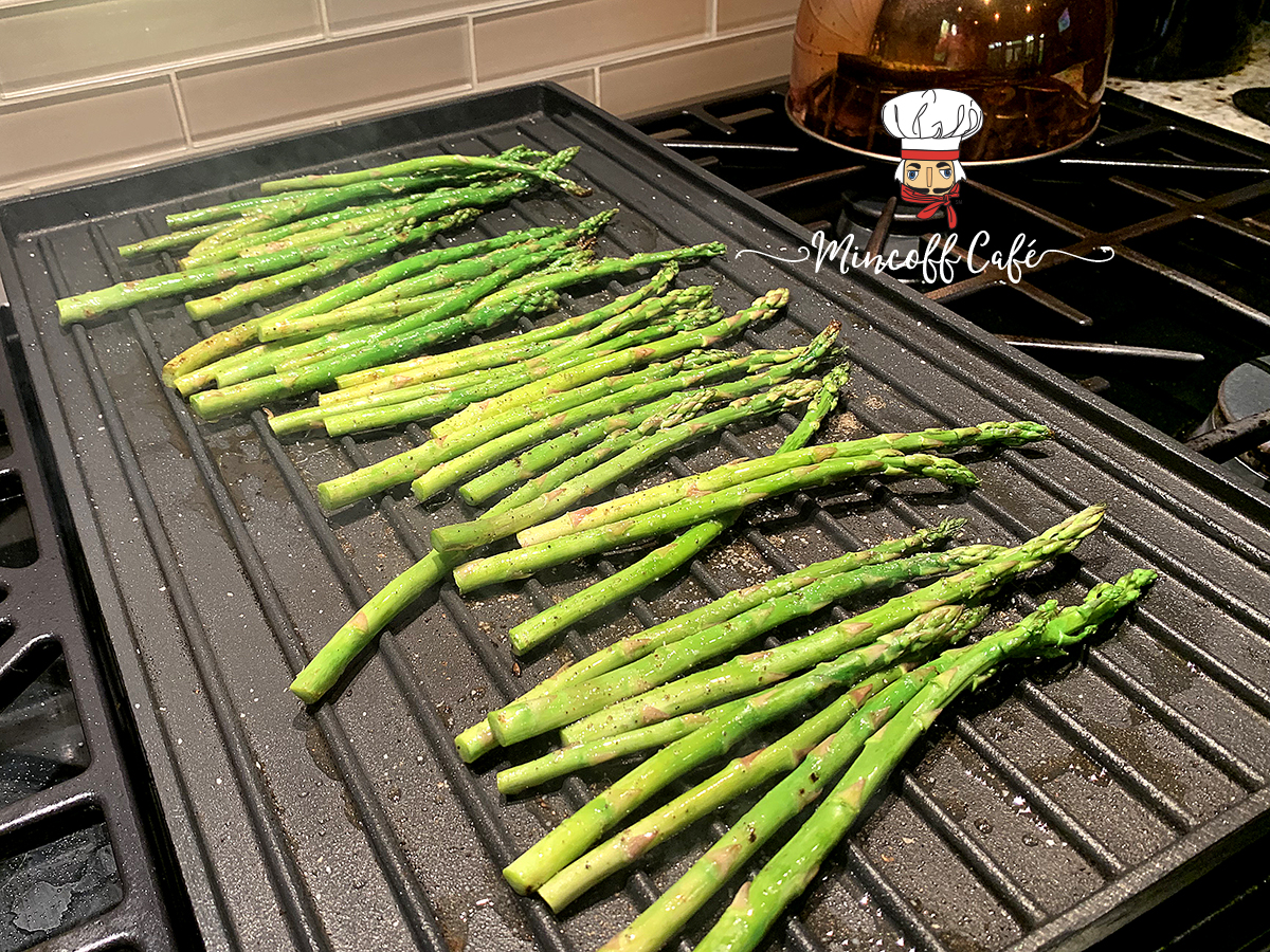 Bright green asparagus laying on an indoor grill.