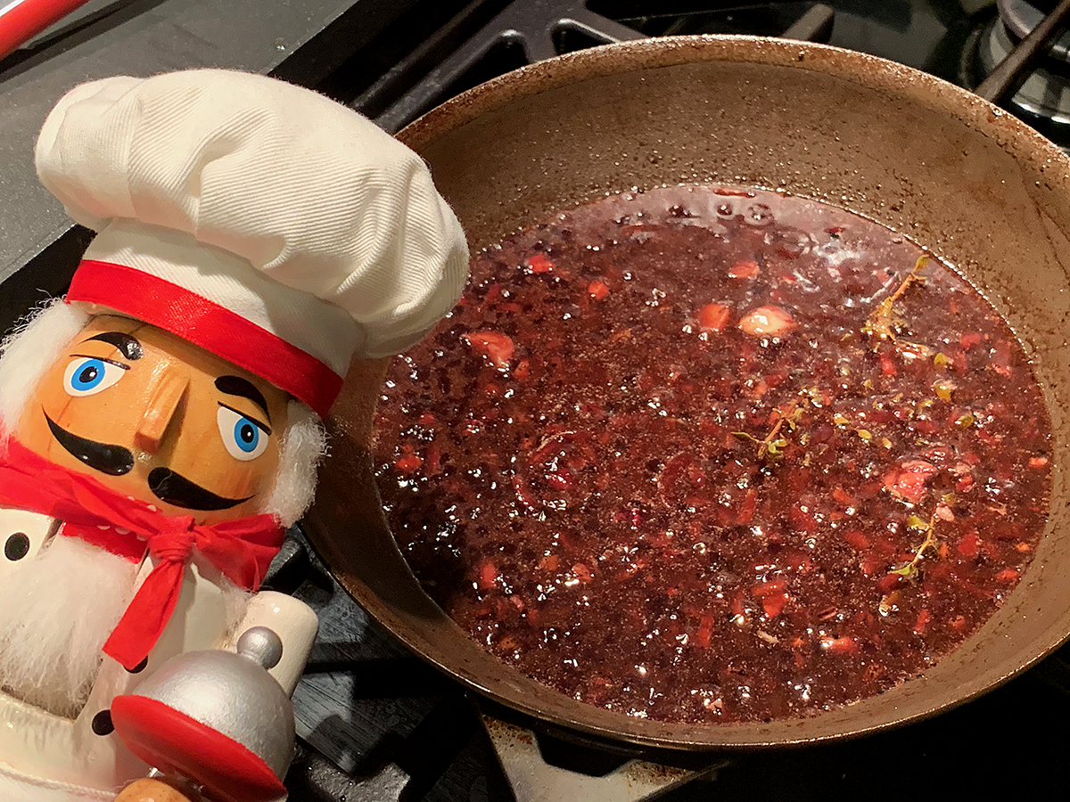 Pomegranate wine sauce in a small skillet. There's also a nutcracker in the foreground who looks like a chef.