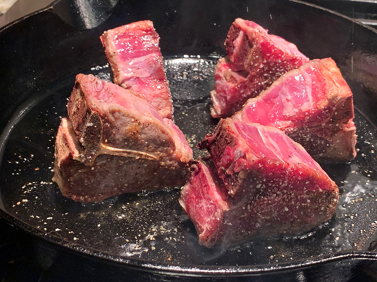 5 lamb loin chops searing on their sides,in an iron skillet.