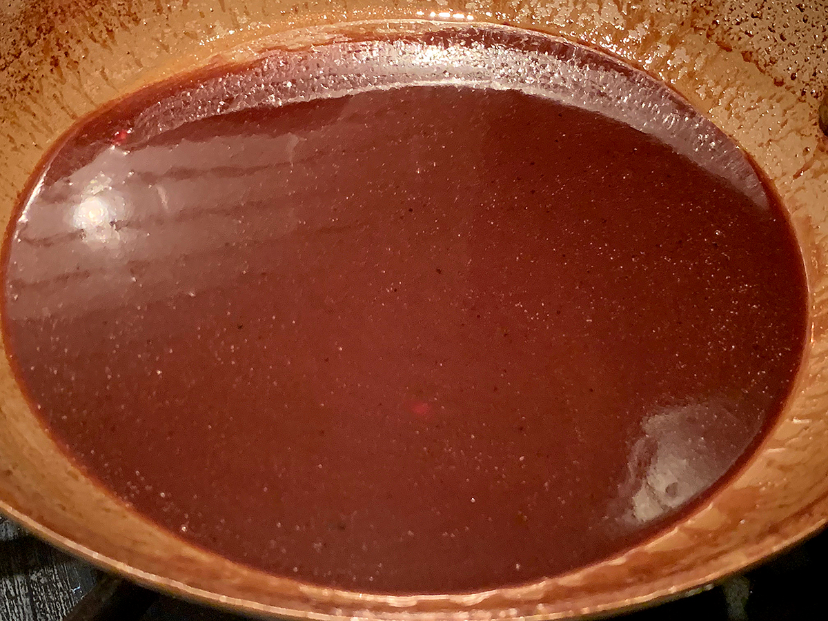 Strained pomegranate wine sauce in a small skillet.