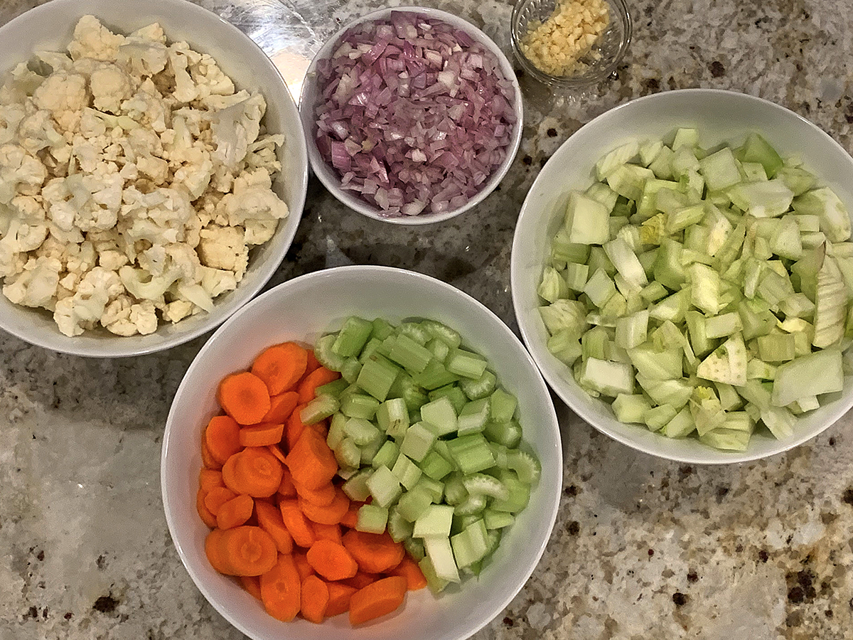 individual bowls filled with chopped cauliflower, fennel bulb, carrots, celery, shallots and garlic. 