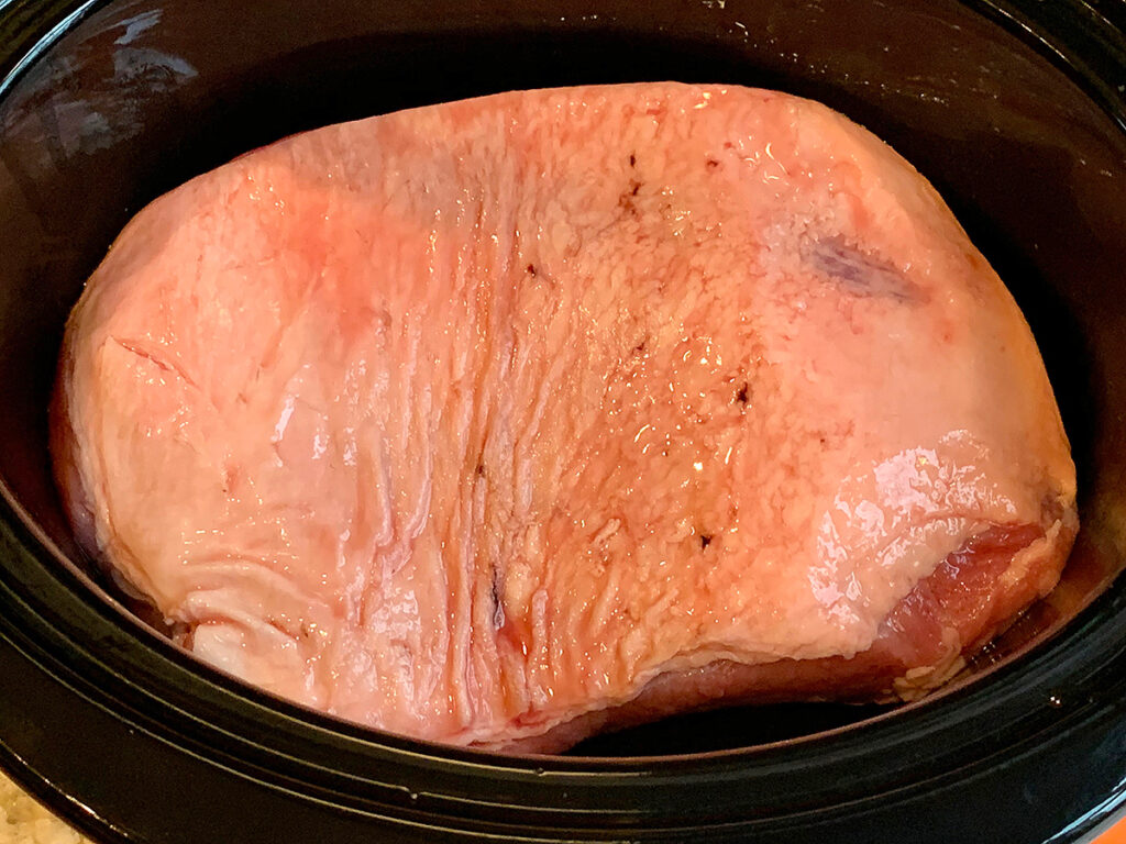Corned beef brisket fat side up in a slow cooker.