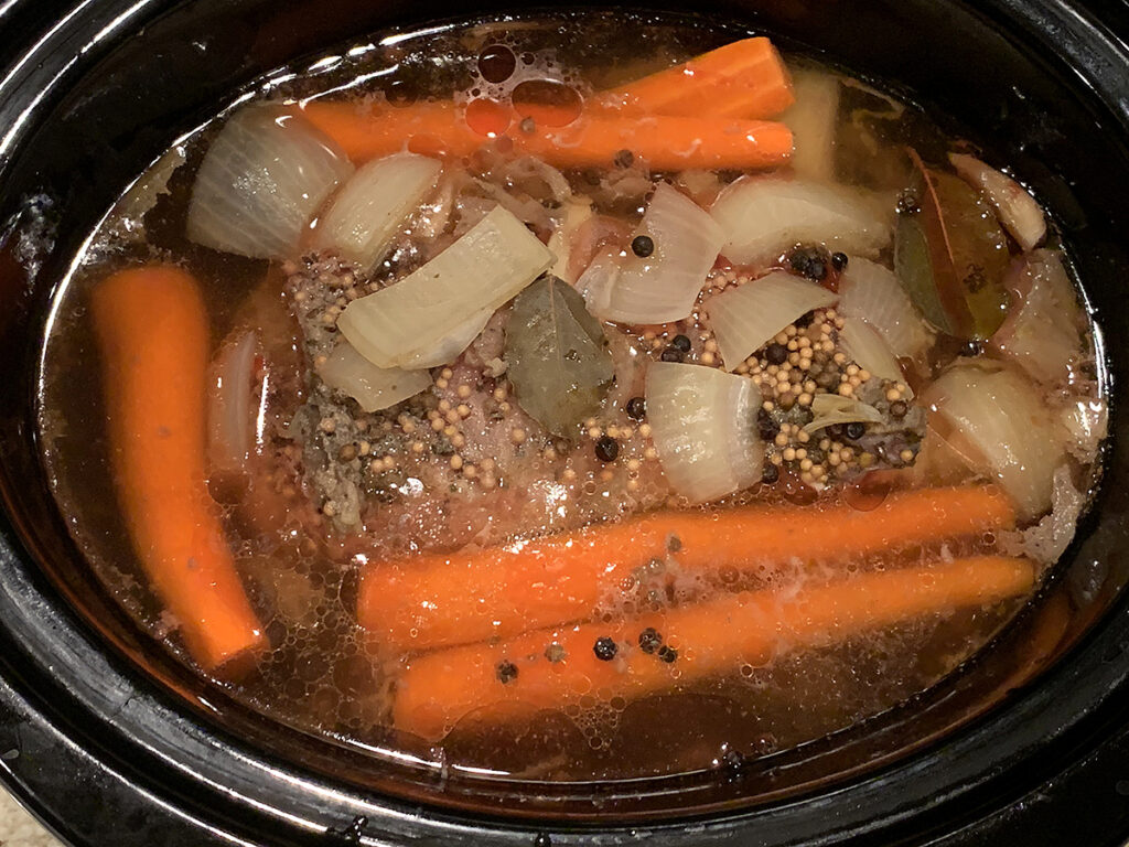 Corned beef, onions and carrots in a slow cooker.