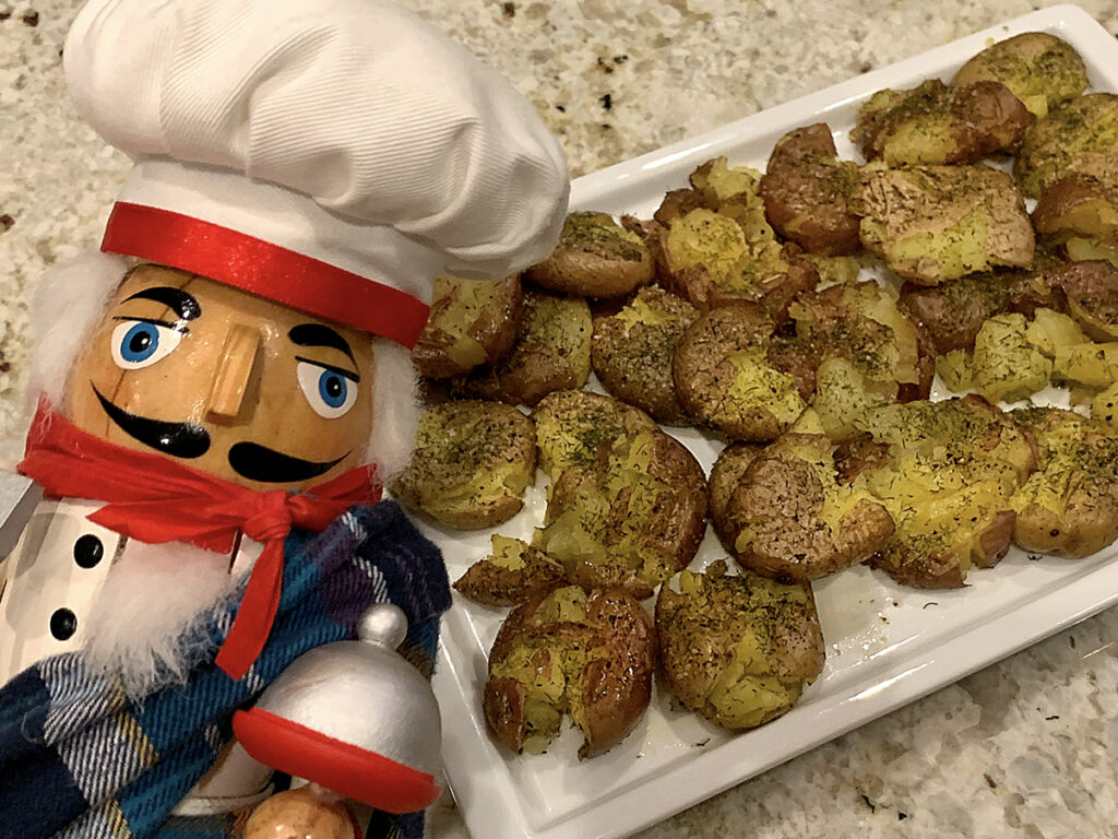 A platter of slightly smashed, but still individual, dill seasoned potatoes. There's a nutcracker in the foreground who looks like a chef and is wearing a kilt for St. Patrick's Day.