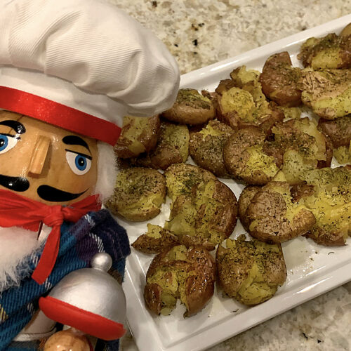A platter of slightly smashed, but still individual, dill seasoned potatoes. There's a nutcracker in the foreground who looks like a chef and is wearing a kilt for St. Patrick's Day.
