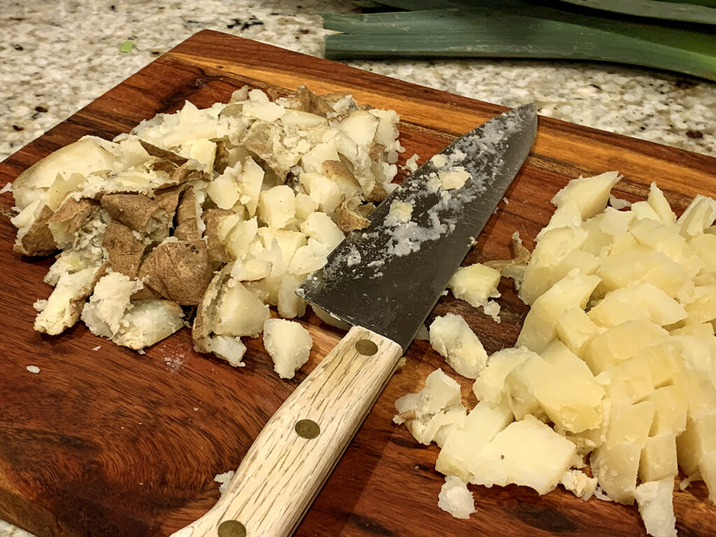 Chopped russet potatoes on a wood cutting board.