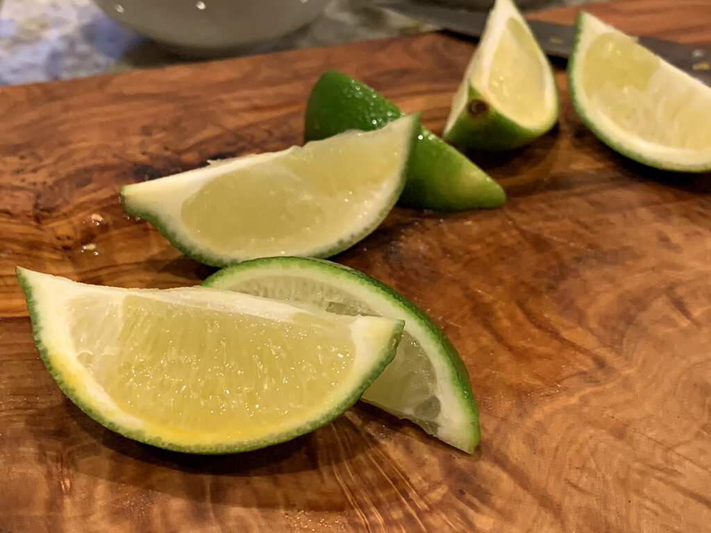 Lime wedges on a wood cutting board.