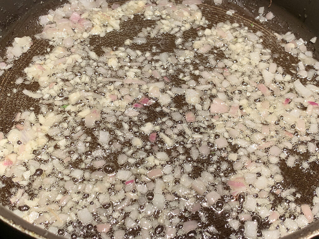 Minced shallots cooking in a skillet.