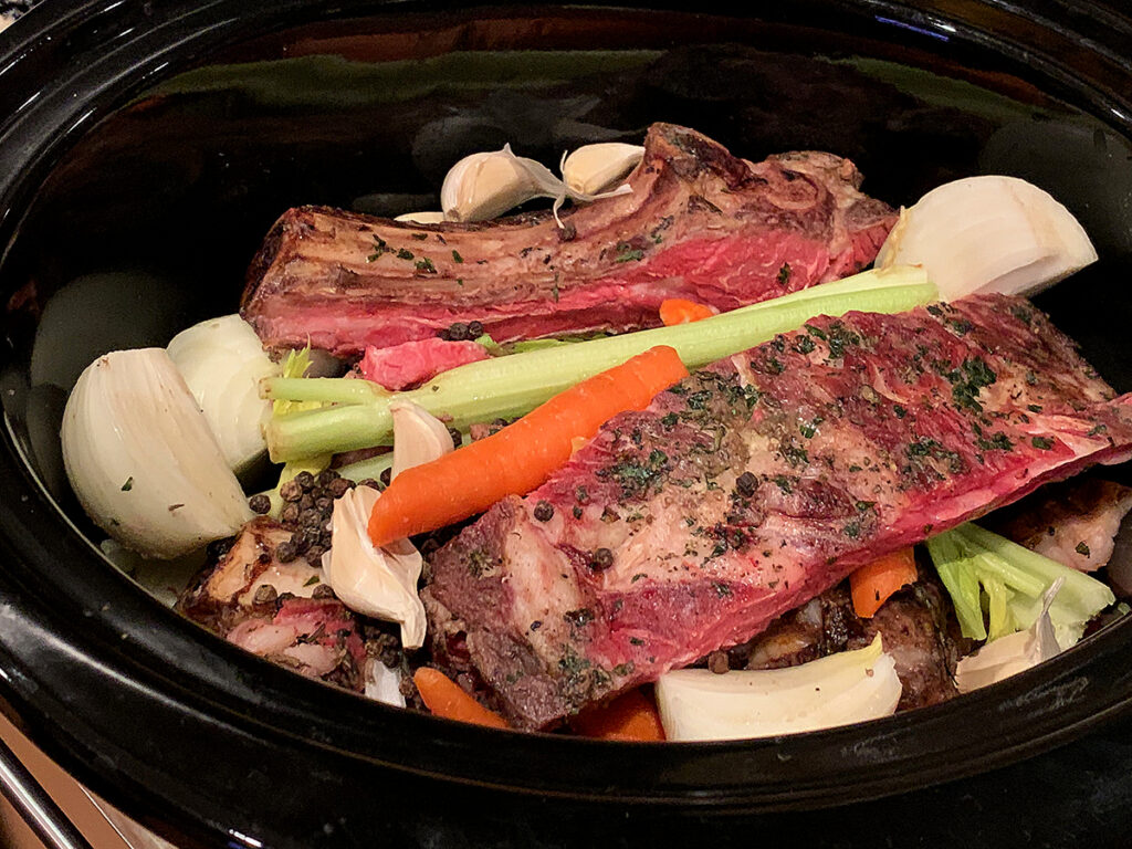Prime rib bones and veggies in a roasting pan.