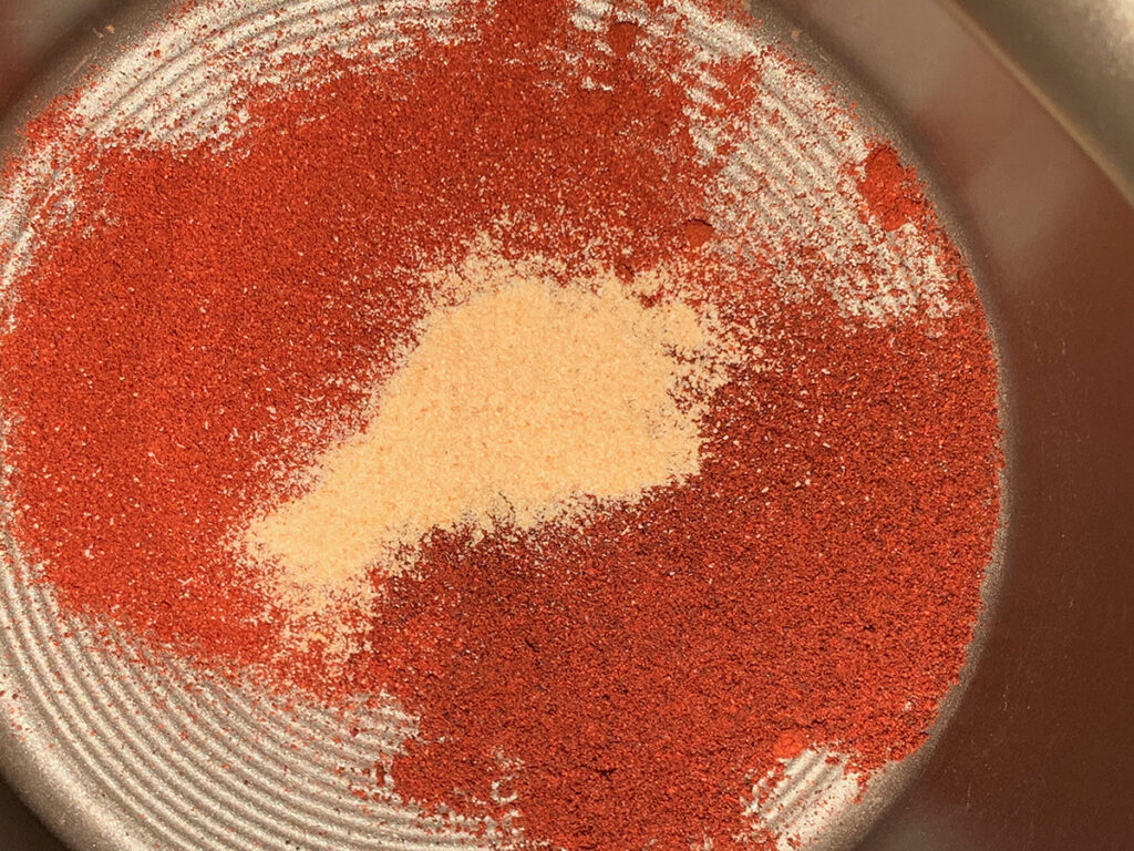 red and tan powdered seasonings in a small sauce pan. 