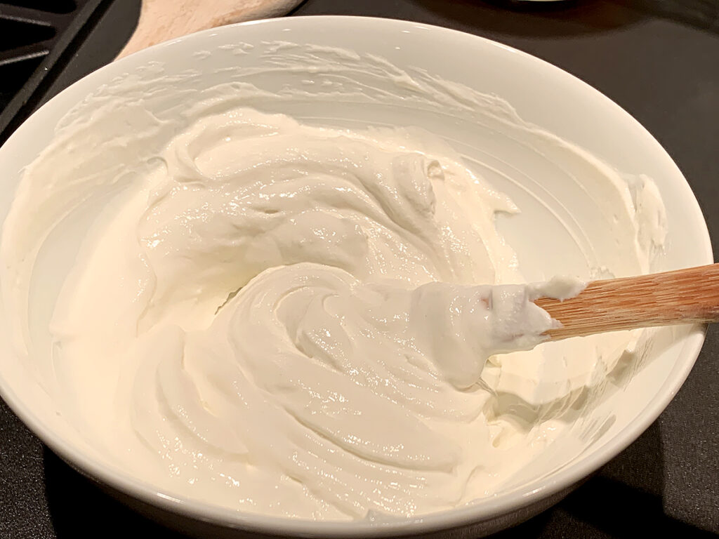 Sour cream and flour being stirred in a small white bowl.