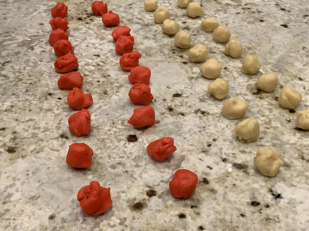 rows and rows of portioned out balls or red dough and white dough.