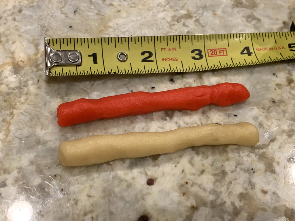 One red and one white dough rolled into 3.5 inch logs of dough with a tape measure above to show their actual size.