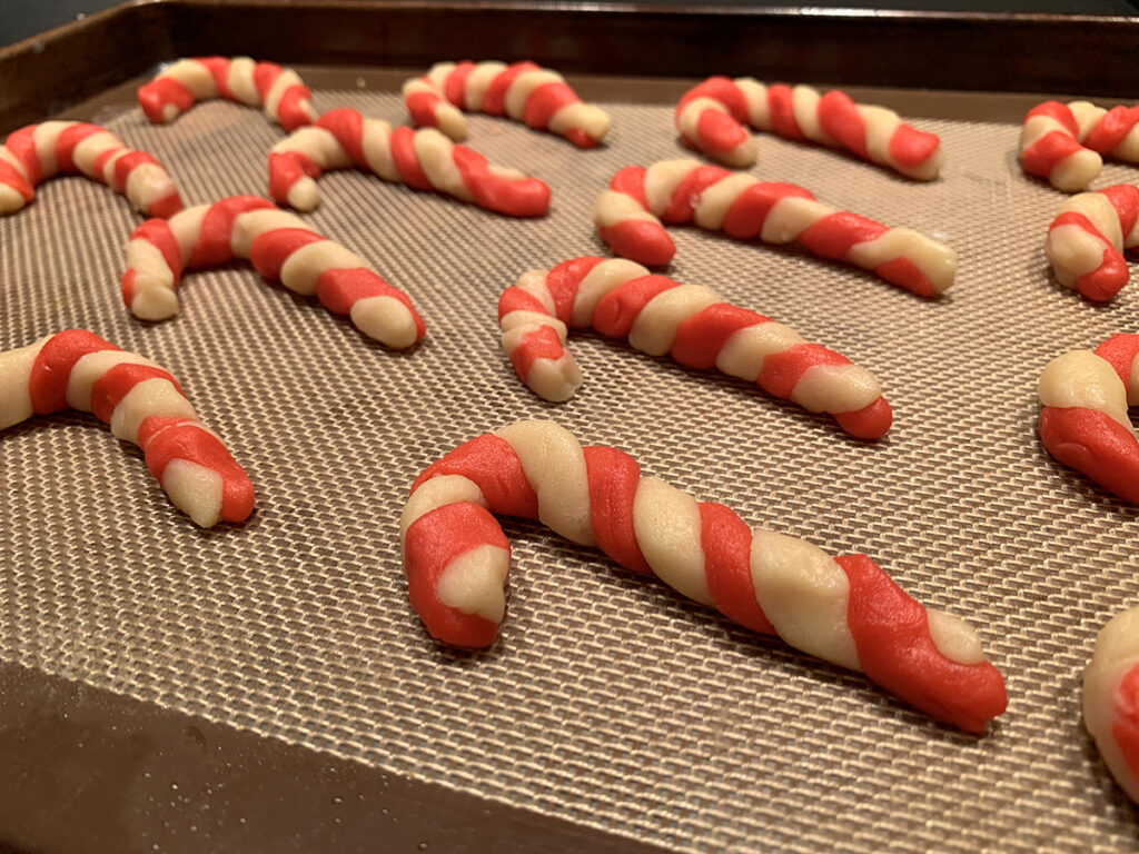 Raw red and white candy cane cookies on a silicone mat.