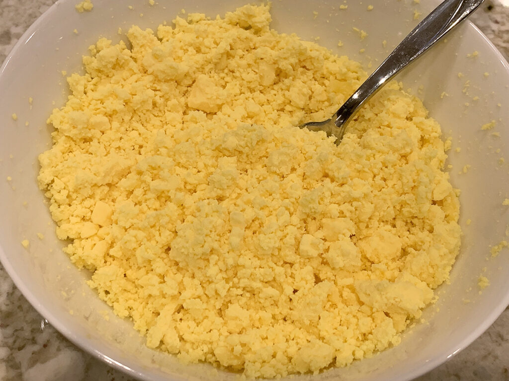 Mashed up hard boiled egg yolks in a white bowl.