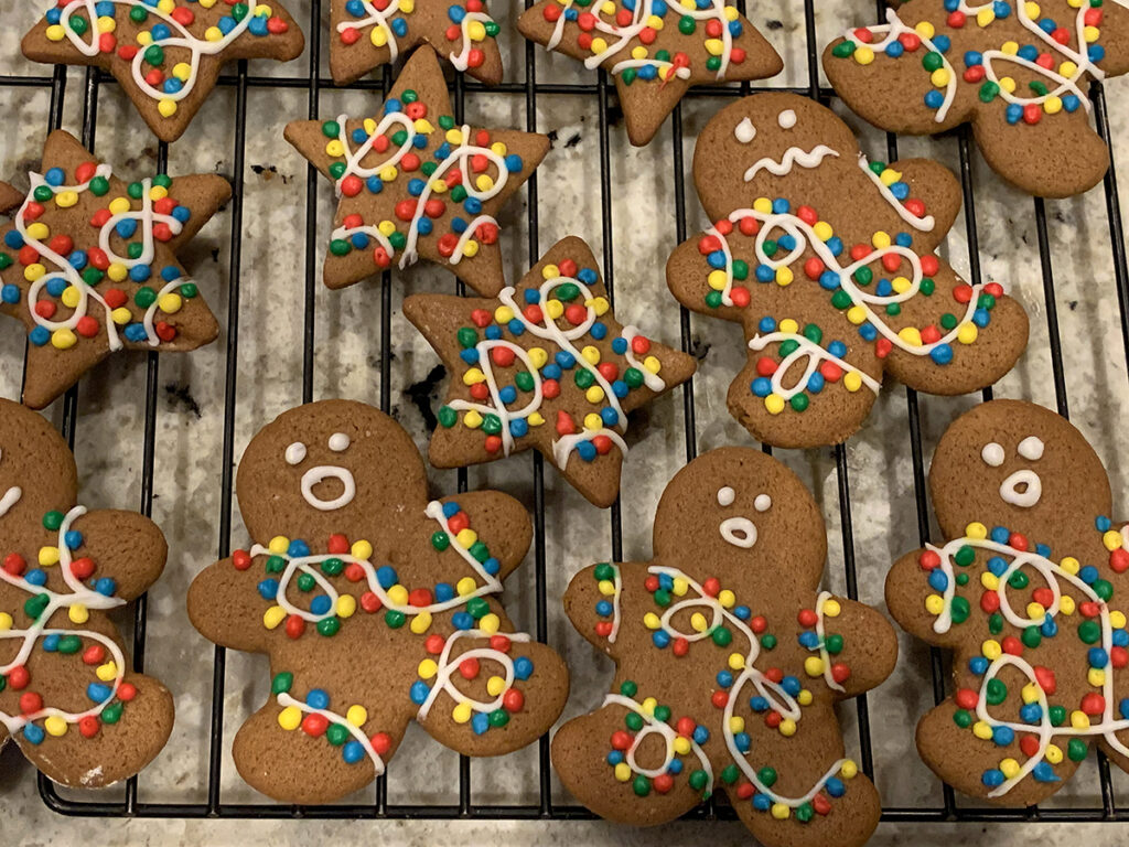 Baked gingerbread cookies shaped like men and stars, decorated to look like they are tangled in colorful lilghts.