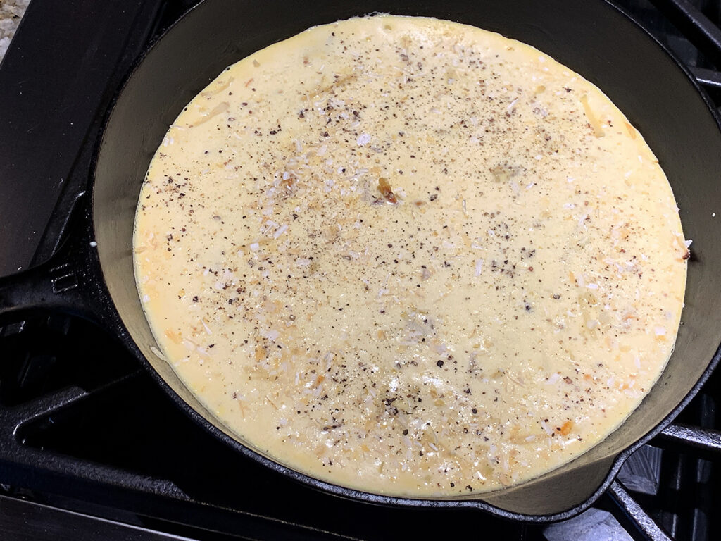 Beaten eggs in an iron skillet.